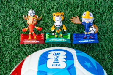 ZHONGSHAN Çin-14 Aralık 2025: 2026 FIFA Dünya Kupası resmi maskotları yatay kompozisyonda futbol sahasında çimenler üzerinde.
