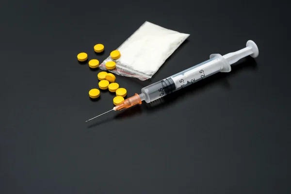 Jednorazowe strzykawki i opakowanie białego proszku i tabletki na czarnym tle — Zdjęcie stockowe
