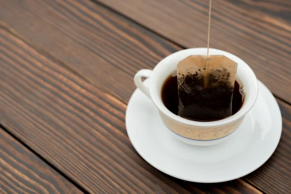 Tazza di tè con bustina di tè su uno sfondo di legno — Foto Stock