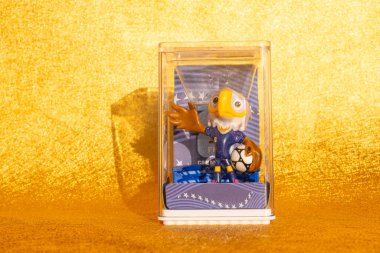 ZHONGSHAN Çin-15 Aralık 2025: resmi maskotlar 2026 FIFA Dünya Kupası için debriyaj şeffaf plastik ekran kutusu yatay kompozisyon altın zemin üzerinde.