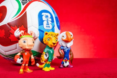 ZHONGSHAN Çin-16 Kasım 2025: 2026 FIFA Dünya Kupası için maskotlar ve futbol yatay kompozisyon kırmızı üzerine.