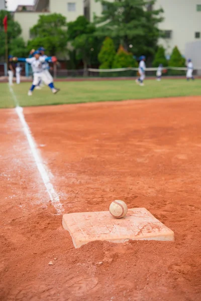 Baseball og base på baseballbane med spillere på bakgrunn – stockfoto