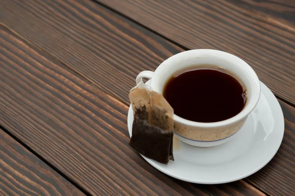 Xícara de chá com teabag em um fundo de madeira — Fotografia de Stock