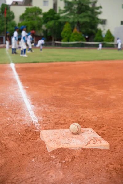 Baseball and base on baseball field with players on background — Stock Photo, Image