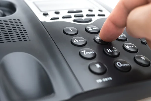 Man ringer upp en svart telefon på nära håll — Stockfoto