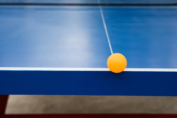 Bola pingpong atinge a borda de uma mesa azul pingpong — Fotografia de Stock