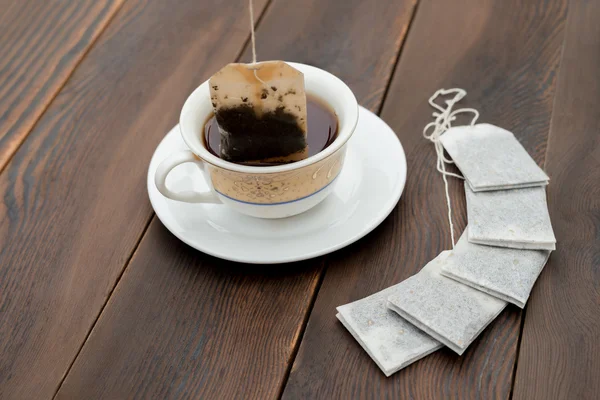 Tasse de thé et de nouveaux sachets de thé sur un fond en bois — Photo