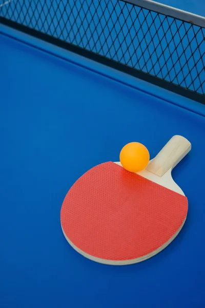 Raqueta de pingpong y bola y red en una mesa de pingpong azul —  Fotos de Stock