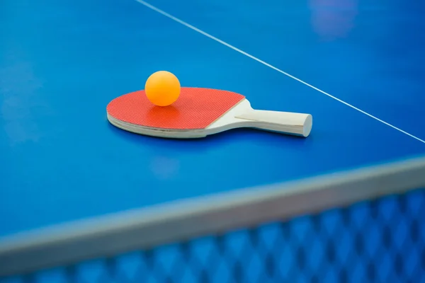 Raqueta de pingpong y bola y red en una mesa de pingpong azul vertical —  Fotos de Stock