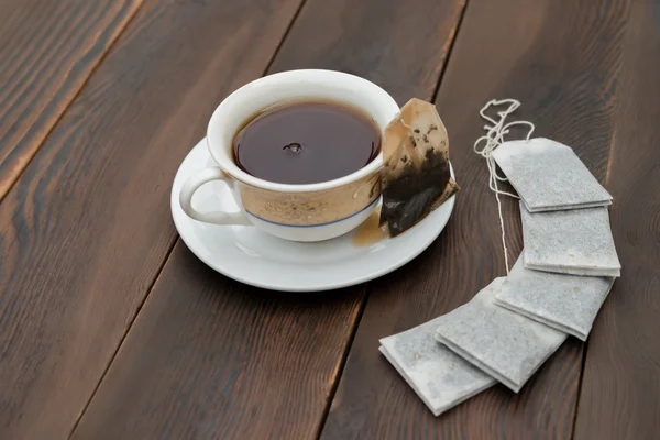 Tasse Tee und neue Teebeutel auf einem hölzernen Hintergrund — Stockfoto