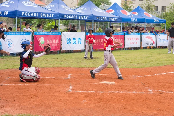 ZHONGSHAN PANDA CUP, ZHONGSHAN, GUANGDONG-july 23: batter of team WuXi Experimental Primary School hit the bal l and the ball bounked up during a match of 2015 National Baseball Championship Group A of Panda Cup against Sports East Road Primary School — стоковое фото