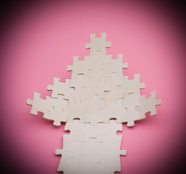 Highlighted jigsaw puzzle shaped like an arrow going up on pink background — Stock Photo, Image