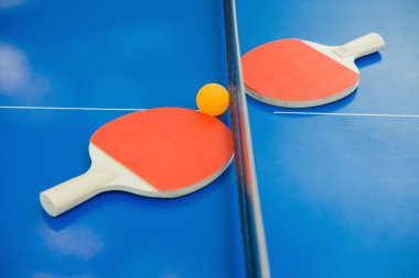 pingpong rackets and ball and net on a blue pingpong table clipart