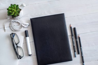 Not defteri ve kulaklığı olan beyaz bir masa görüntüsü.