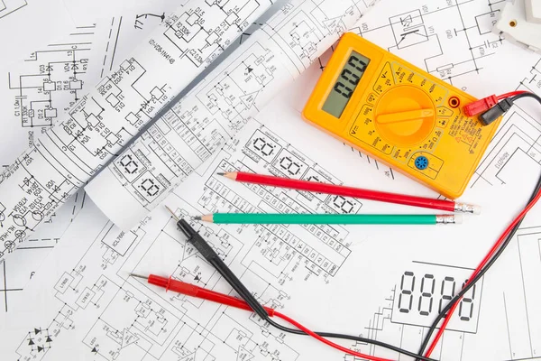 digital multimeter and pencils on paper electrical engineering drawings