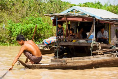 Chong Kneas, Kamboçya-6 Ağustos 2009: Siem Reap yakınlarındaki bir yüzen ev köyünde, bir adam mallarını satmak için taşır.