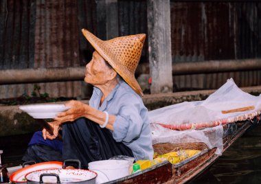 Damnoen Saduak, Tayland-9 Ağustos 2009: İnsanlar Bangkok yakınlarındaki yüzen bir pazarda teknesinden hediyeler satıyor