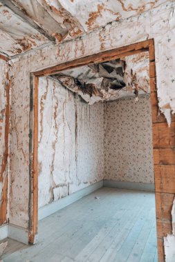 Extremely damaged wallpaper with collapsing ceiling, likely from water damage at an abandoned home in the Bannack ghost town of Montana clipart