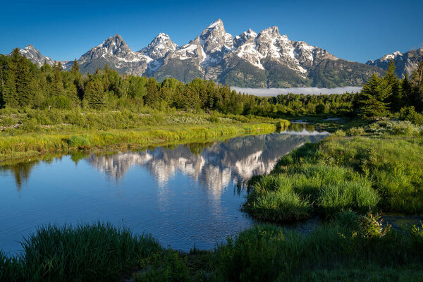 Schwabachers Landing in the early morning in Grand Teton National Park, with mountain reflections on the water creek