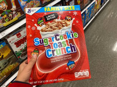 Maple Grove, Minnesota - 15 Kasım 2020: Alışveriş yapan kişinin elinde bir kutu Şekerli Kurabiye Tostu Noel Crunch Noel renklerinde özel yapım mısır gevreği var.