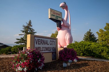 Vernal, Utah - September 24, 2020: Sign for Vernal Utah, with its famous pink dinosaur statue, taken at dusk clipart