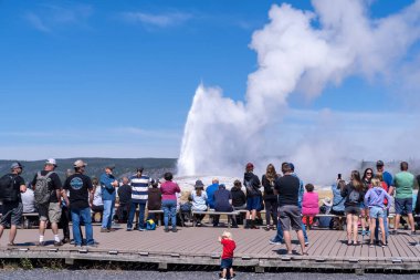 Wyoming, ABD - 10 Ağustos 2021: Yellowstone Ulusal Parkı 'nda Old Faithful' un patlaması için tahta kaldırımlar boyunca turist kalabalığı bekliyor