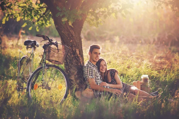 Attraktivt par njuter av romantisk solnedgång picknick på landsbygden. — Stockfoto