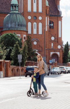 Genç bir anne ve oğul eski kasabada scooter 'a biniyor. Küçük çocuklu bir kadın mobilete biniyor. Aile seyahati anne ve bebek. Bydgoszcz 'deki köprüde yürü. Polonya.