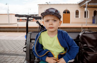 Anaokulu çocuğu bankta oturuyor. Şapkalı çocuk. Çocuk.