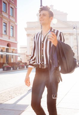 Genç bir adam şehirde dolaşıyor. Şık giyinmiş şık bir adam ve kolunda siyah bir ceket var. Kahveli çocuk dışarıda..