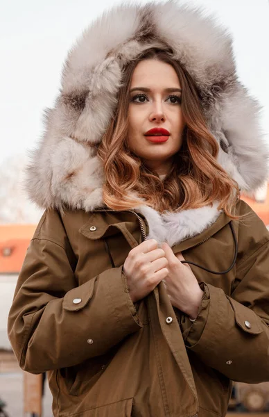 頭上にフード付きのダウンジャケットを着たスタイリッシュな女の子 赤い唇の若い女性 路上で毛皮の喫煙者の美しい少女の肖像画 屋外撮影 — ストック写真