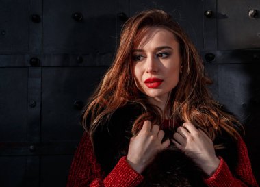 Kış şehrinde zarif bir kız yürüyor. Sarışın, güzel bir bayan. Güzel sarışın kadın portresi, kalın kıyafetler giymiş. Kapüşonlu, siyah pantolonlu ve botlu bir kadın..