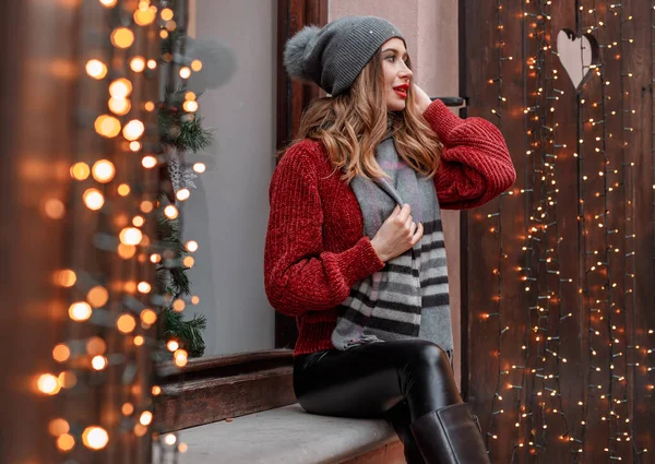 スタイリッシュなニット帽とスカーフを身に着けている クリスマス市の市場を照明や装飾品やカルーセルを背景に歩く女性は — ストック写真