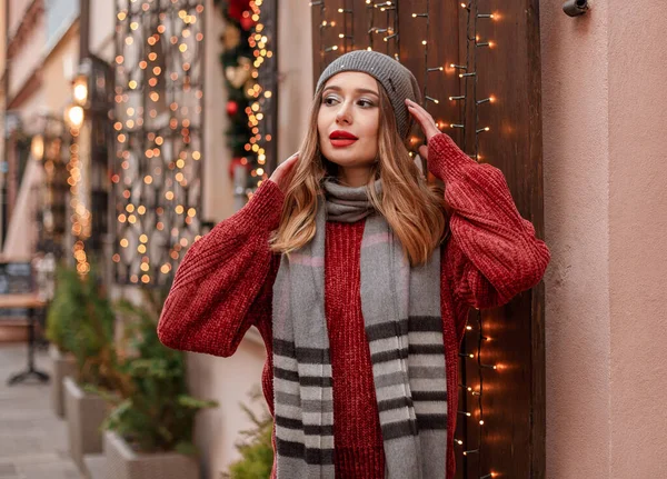 スタイリッシュなニット帽とスカーフを身に着けている クリスマス市の市場を照明や装飾品やカルーセルを背景に歩く女性は — ストック写真