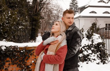 Nazik bir kucaklaşmada sevgi dolu bir çift. Adam kız arkadaşını öpüyor. Sevgililer Günü. Genç adam kış parkında kız arkadaşına sarılıyor..