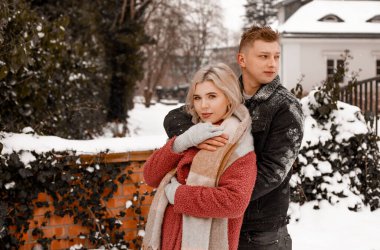 Nazik bir kucaklaşmada sevgi dolu bir çift. Adam kız arkadaşını öpüyor. Sevgililer Günü. Genç adam kış parkında kız arkadaşına sarılıyor..