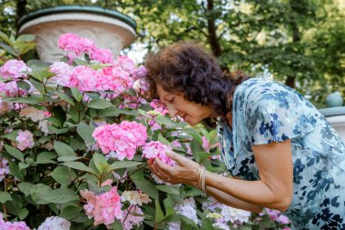 Çiçekli bir kadın. Bahçede çalışan kıdemli İspanyol kadın. Elinde çiçeklerle yürüyen yaşlı bir kadının yakın plan portresi. Park.