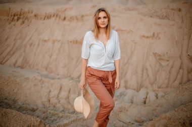 Genç bir kadın şapkasıyla kumlu sahili keşfediyor. Hippi kız, doğa çölünde genç bir gezgin. Bir kadın çölde buluşmak için yürür. Kadın yürüyor.