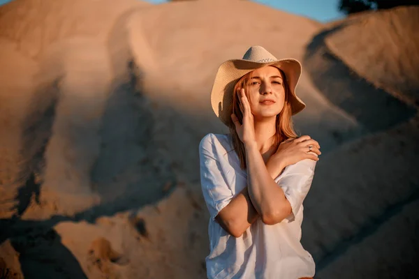 Mujer joven sonriendo en la playa. Una chica una arenosa con sombrero. Hermosa chica en una cantera de arena. — Foto de Stock