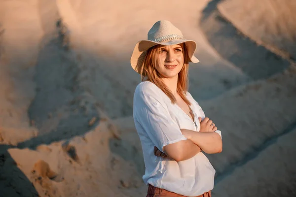 Mujer joven sonriendo en la playa. Una chica una arenosa con sombrero. Hermosa chica en una cantera de arena. — Foto de Stock