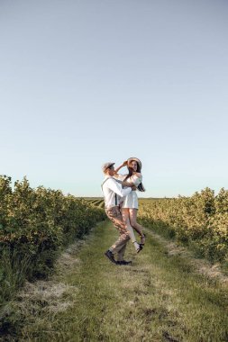 Hipster boho tarzı bağımsız kıyafetler giyen, kırsalda aşık genç bir çift, erkek kadını elinde tutuyor. Çiftler dışarıda eğleniyor..