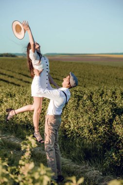 Hipster boho tarzı bağımsız kıyafetler giyen, kırsalda aşık genç bir çift, erkek kadını elinde tutuyor. Çiftler dışarıda eğleniyor..