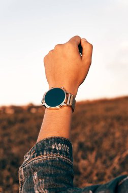 Sığ bir odak noktası, kot ceketli bir kadının eline bir saat taktı.