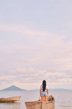 Managua Gölü 'nün ortasında teknede duran bir kadının gökyüzüne bakışının arkası.