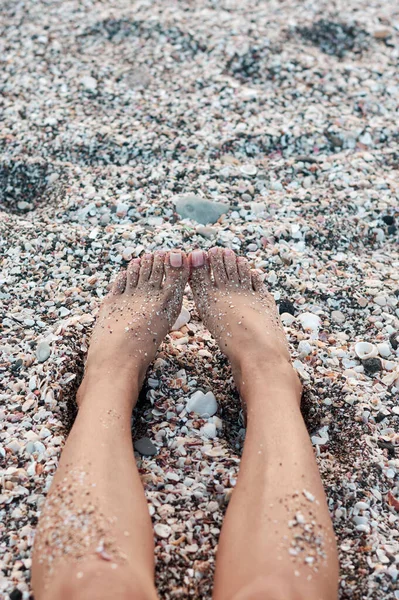 Pés Uma Mulher Deitada Numa Praia Cheia Conchas — Fotografia de Stock