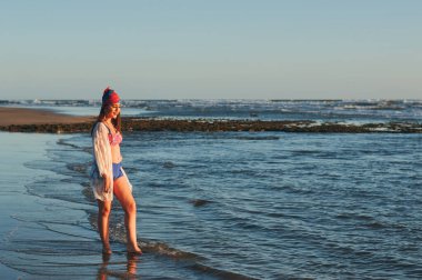 Deniz kıyısında mayo giymiş mutlu bir kadın.