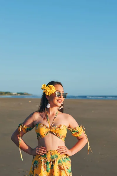 Sahilde sarı yaz kıyafeti giymiş bir kadının portresi.