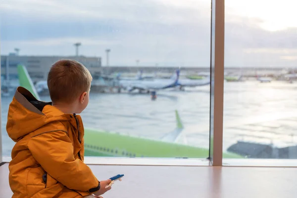 大きな窓の空港の黄色いジャケットの少年. ストック画像