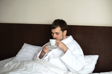 Beyaz elbiseli genç bir adam yatakta..