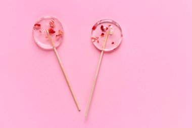 Pembe arka planda iki şeffaf lolipop..